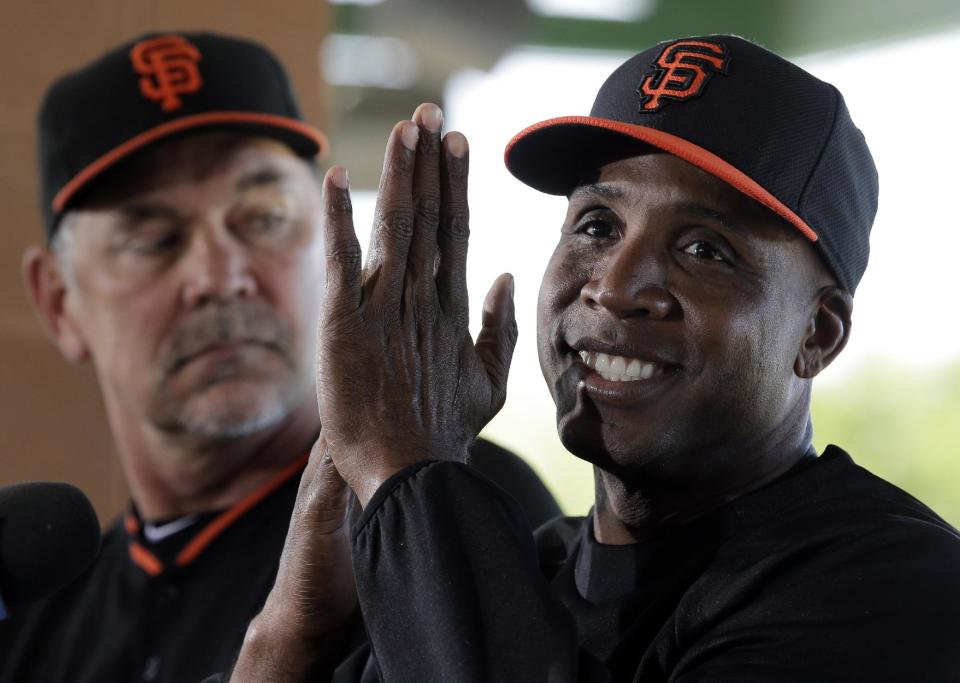 San Francisco Giants manager Bruce Bochy, left, listens as former player Barry Bonds speaks at a news conference before a spring training baseball game in Scottsdale, Ariz., Monday, March 10, 2014. Bonds starts a seven day coaching stint today. (AP Photo/Chris Carlson)