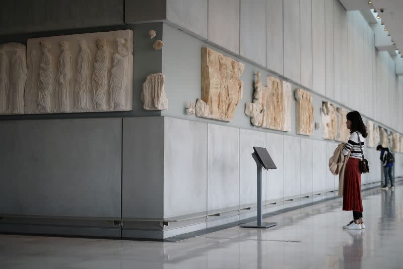 Visitors look at original sculptures and plaster cast copies of the frieze of the Parthenon temple, as they visit the Parthenon Gallery of the Acropolis Museum, in Athens