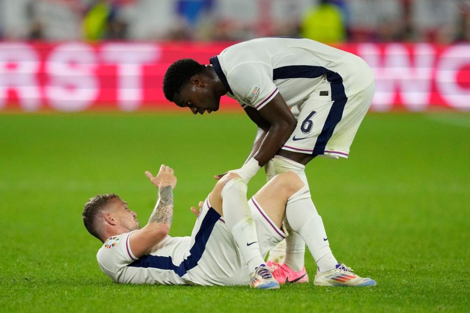 Marc Guehi helps teammate Kieran Trippier get up after a foul during a Group C match between Serbia and England (Andreea Alexandru / AP)