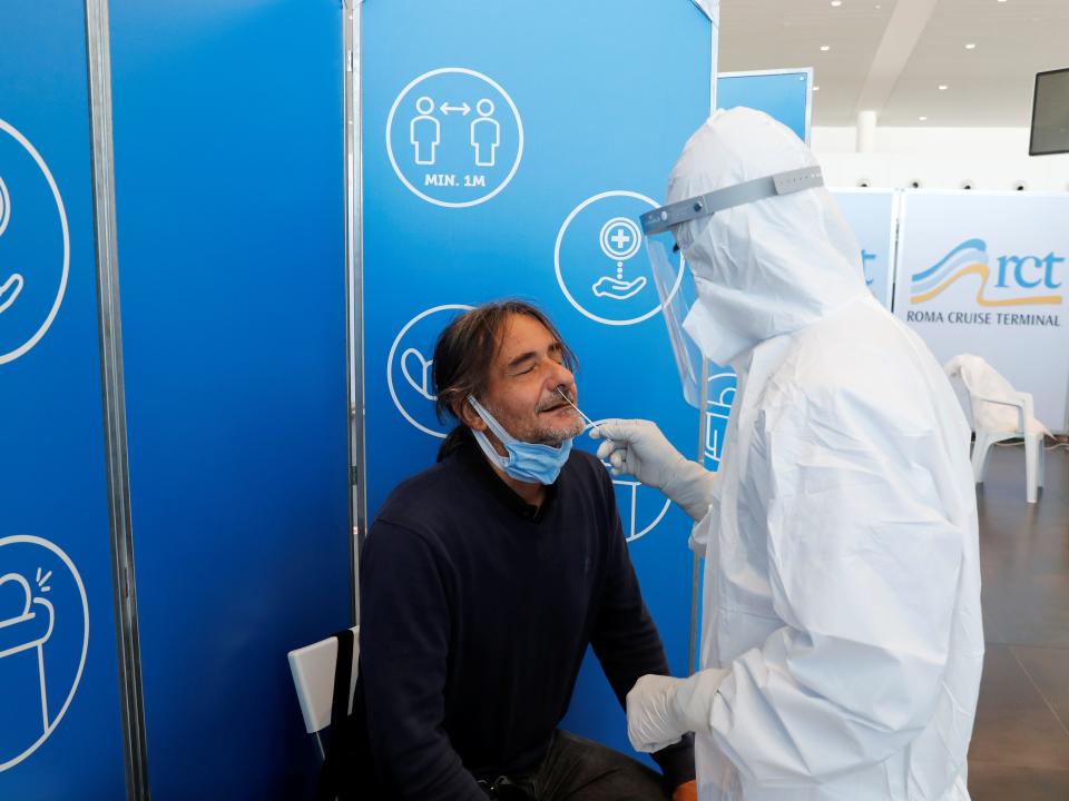 This image shows a man getting a swab from another person in a hazmat suit.