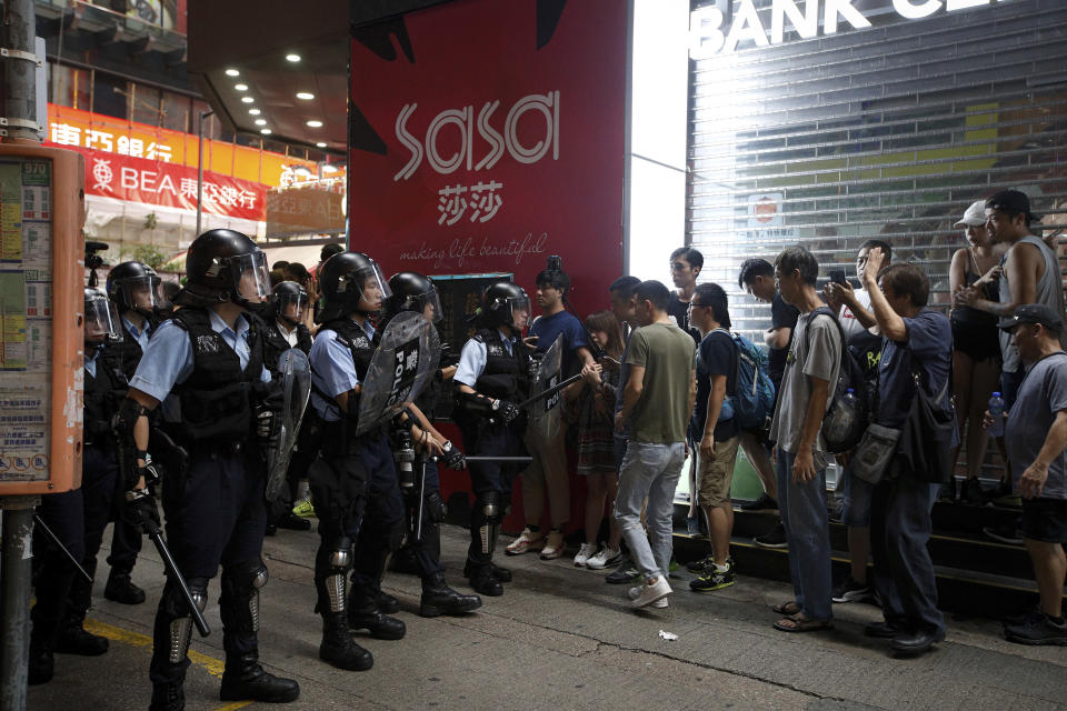 In this July 7, 2019, photo, riot police prevent people, some are mainland Chinese tourists, from crossing a street during a face-off with protesters at the Mongkok, a popular place with mainland Chinese tourists in Hong Kong. It's still the world's "freest" economy, one of the biggest global financial centers and a scenic haven for tycoons and tourists, but the waves of protests rocking Hong Kong are exposing strains unlikely to dissipate as communist-ruled Beijing's influence grows. (AP Photo/Andy Wong)