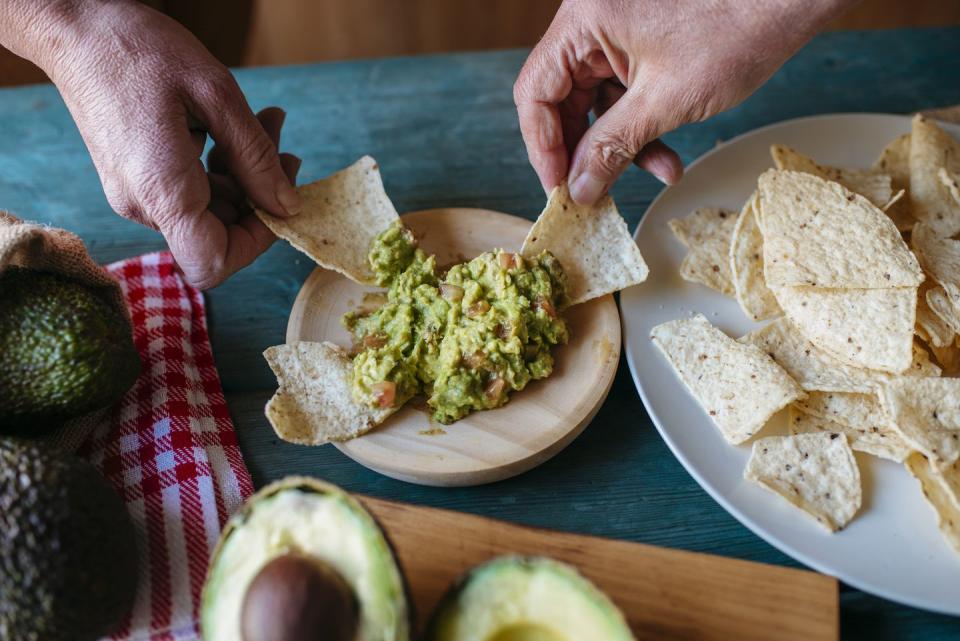 november holidays two hands dipping tortilla chips in guacamole