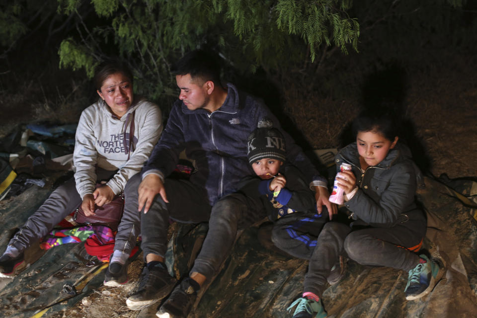 A family from Honduras sits on the ground after they were smuggled on an inflatable raft across the Rio Grande, in Roma, Texas Saturday, March 27, 2021. Roma, a town of 10,000 people with historic buildings and boarded-up storefronts in Texas' Rio Grande Valley, is the latest epicenter of illegal crossings, where growing numbers of families and children are entering the United States to seek asylum. (AP Photo/Dario Lopez-Mills)