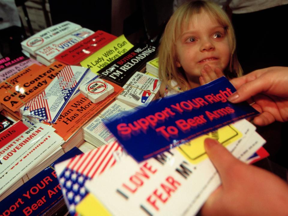 A child is beside a table of bumper stickers at an NRA convention in 1995.