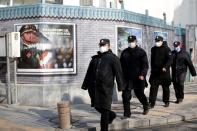 Security personnel wearing masks walk along the Financial Street in central Beijing