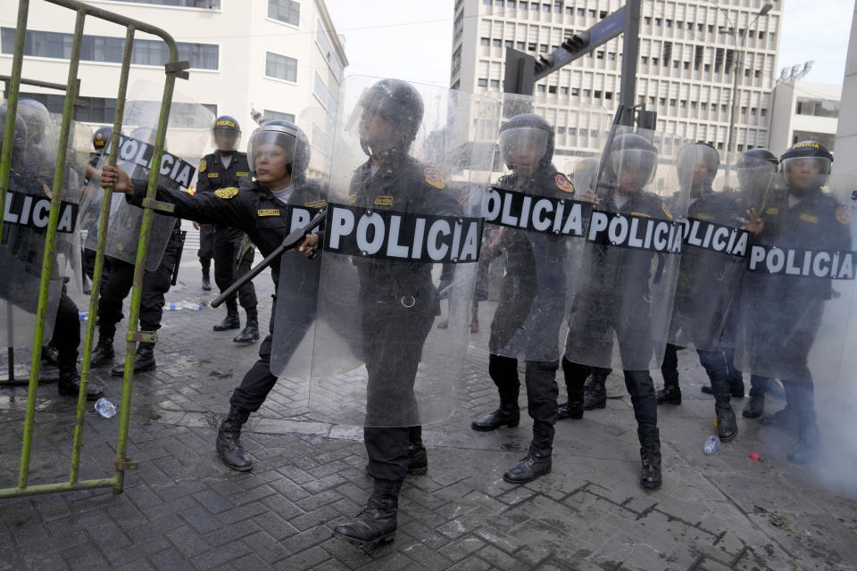 Police in riot gear hold their ground at a barricade during clashes with anti-government protesters who traveled to the capital from across the country to march against Peruvian President Dina Boluarte in Lima, Peru, Thursday, Jan. 19, 2023. Protesters are seeking immediate elections, Boluarte's resignation, the release of ousted President Pedro Castillo and justice for up to 48 protesters killed in clashes with police. (AP Photo/Martin Mejia)