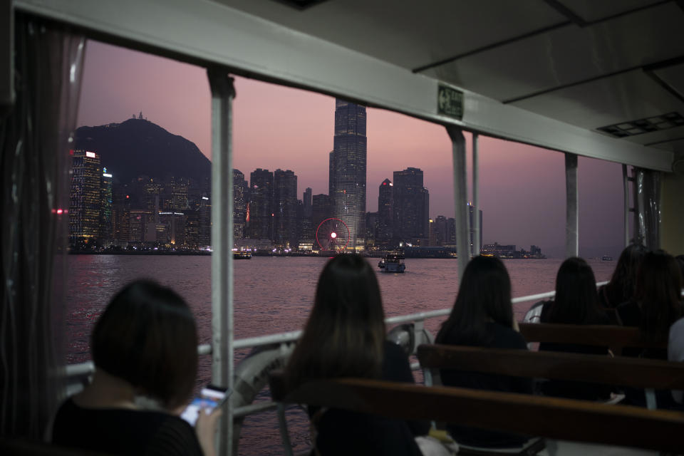 In this Oct. 10, 2019 photo, people ride in a ferry from Hong Kong Island to Kowloon as the sun sets in Hong Kong. The body-blow of months of political protests on Hong Kong’s tourism is verging on catastrophic for one of the world’s great destinations. Geared up to receive 65 million travelers a year, the city’s hotels, retailers, restaurants and other travel-oriented industries are suffering. But some intrepid visitors came specifically to see the protests and are reveling in deep discounts and unusually short lines at tourist hotspots.(AP Photo/Felipe Dana)