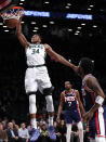 Milwaukee Bucks forward Giannis Antetokounmpo (34) dunks as Brooklyn Nets Kevin Durant (7) and Kyrie Irving watch during the first half of an NBA basketball game Thursday, March 31, 2022, in New York. (AP Photo/Noah K. Murray)