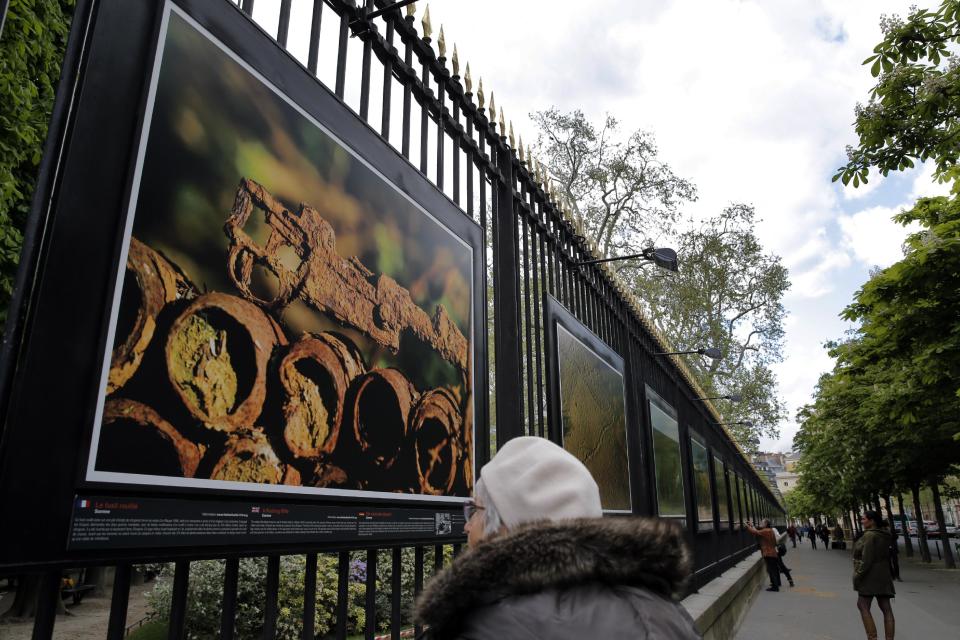 A woman watches "A rusting rifle" a picture by British photographer Michael St Maur Sheil at the Paris Luxembourg gardens, Tuesday, April 8, 2014 as part of an exhibition " Fields of Battle - Lands of Peace 14-18 ". Captured over a period of seven years, Michael’s photography combines a passion for history and landscape and presents a unique reflection on the transformation of the battlefields of the Great War into the landscape of modern Europe. (AP Photo/Christophe Ena)