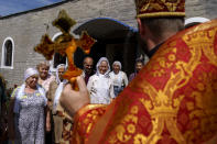 Archpriest Oleksandr Kondratyuk, right, blesses congregants with holy water outside St. Michael's Ukrainian Orthodox Church of the Moscow Patriarchate for Savior of the Honey Feast Day in Pokrovsk, Donetsk region, eastern Ukraine, Sunday, Aug. 14, 2022. (AP Photo/David Goldman)