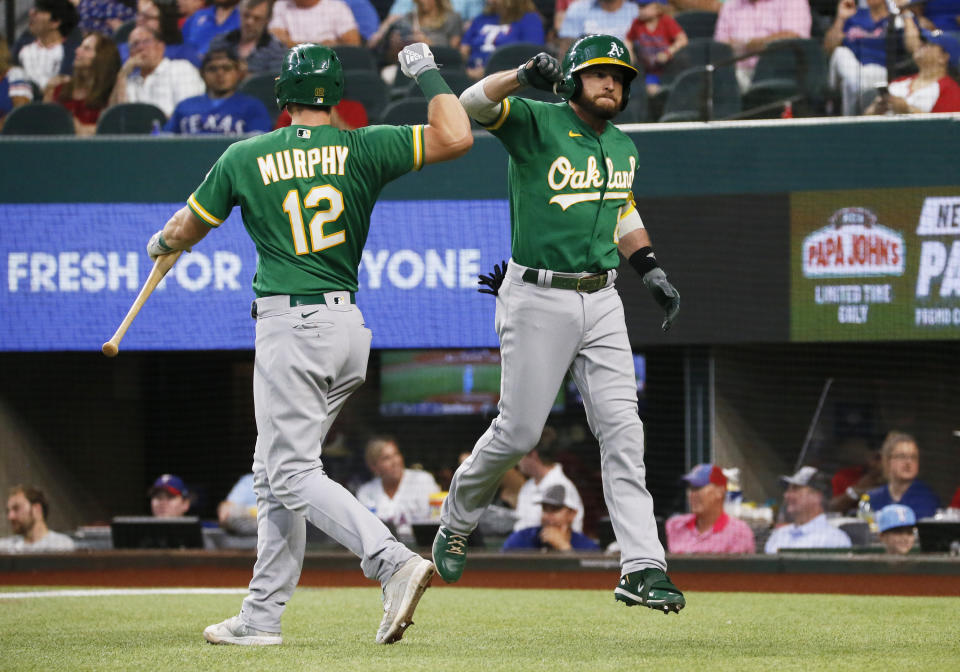 Oakland Athletics' Jed Lowrie, right, is greeted at the plate by Sean Murphy, left, after hitting a solo home run against the Texas Rangers during the second inning of a baseball game in Arlington, Texas, Sunday, July 11, 2021. (AP Photo/Ray Carlin)