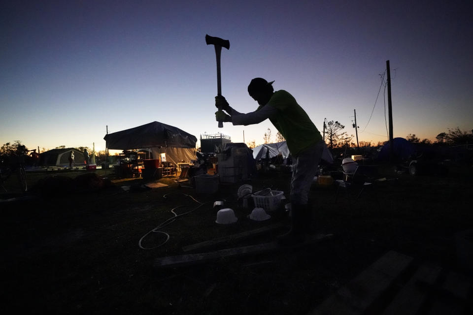 Ricky Trahan chops wood to make a fire on his property after their home was destroyed by both Hurricane Laura and Hurricane Delta in Lake Charles, La., Friday, Dec. 4, 2020. The family is living in tents, with their son, his fiancee and their son Ricky III living in a loaned camper there. His sister's family's home is now gutted and they are living in a camper on the same property. (AP Photo/Gerald Herbert)