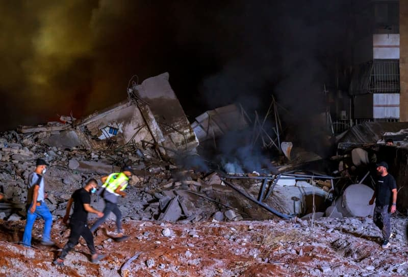 Rescue workers gather at the site of a massive Israeli airstrike on Hezbollah's pro-Iranian headquarters in Beirut's southern suburbs. Marwan Naaman/dpa