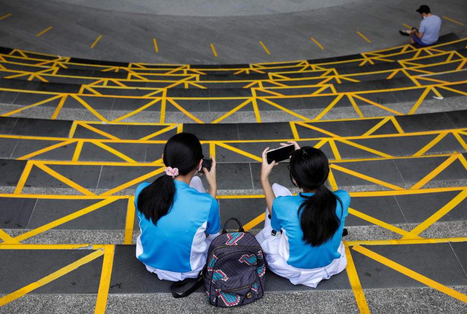 People sit next to social distancing stickers that demarcate the public seating areas of a mall, amid the coronavirus disease (COVID-19) pandemic, in Singapore October 6, 2021. REUTERS/Edgar Su