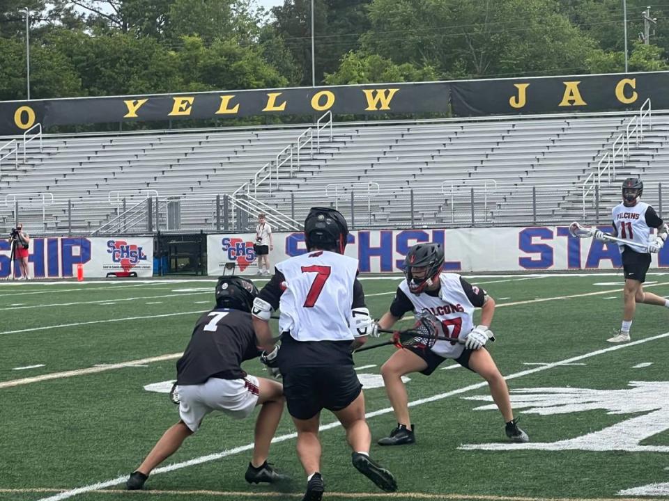 Nation Ford’s Will Alvarado (7, white) and Vance Matthews (17, white) try to bracket Wando’s Bragg McConnell in the third quarter of the SCHSL 5A Boys Lacrosse State Championship Game.