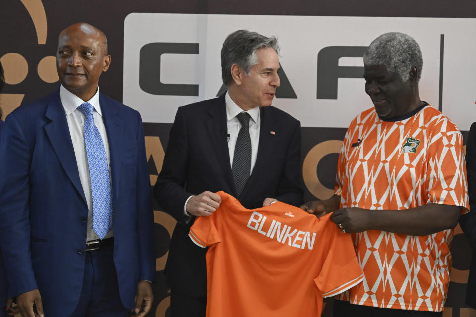 US Secretary of State Antony Blinken, center, receives a football jersey with his name on from Prime Minister of Ivory Coast Robert Beugre Mambe, second right, as President of the Confederation of African Football (CAF) Patrice Motsepe, left, looks on, as they attend the Africa Cup of Nations (CAN) 2024 group A soccer match between Equatorial Guinea and Ivory Coast at the Alassane Ouattara Stadium in Ebimpe, Abidjan Abidjan, Ivory Coast, Monday, Jan. 22, 2024. (Andrew Caballero-Reynolds/Pool Photo via AP)