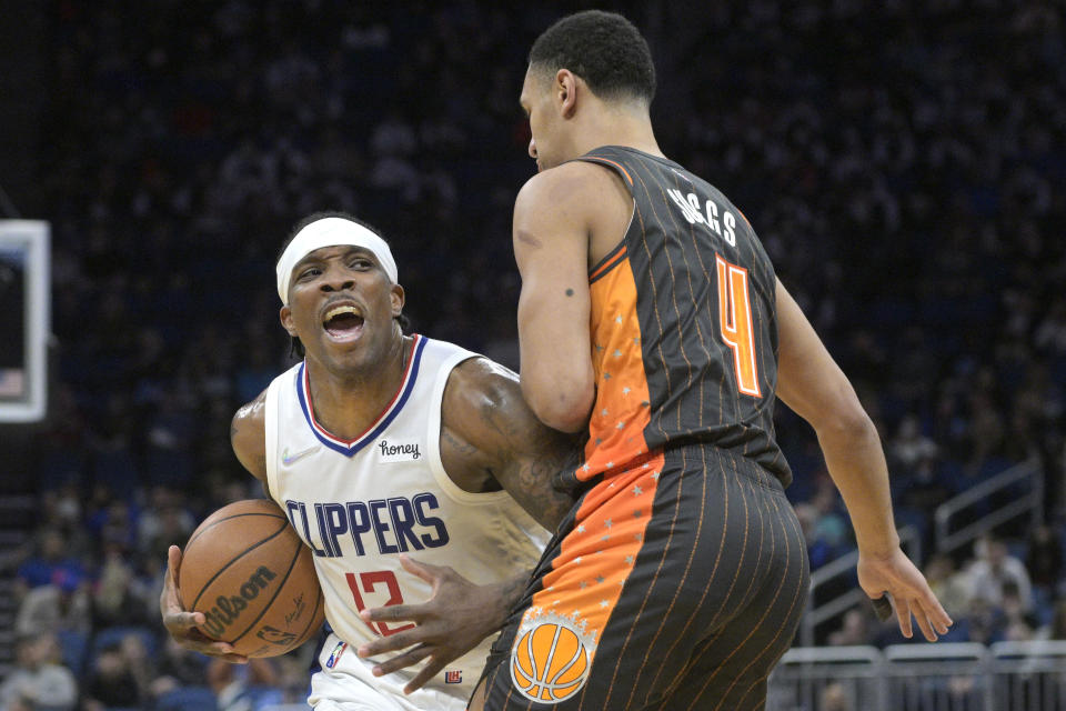 Los Angeles Clippers guard Eric Bledsoe (12) is defended by Orlando Magic guard Jalen Suggs (4) during the first half of an NBA basketball game, Wednesday, Jan. 26, 2022, in Orlando, Fla. (AP Photo/Phelan M. Ebenhack)