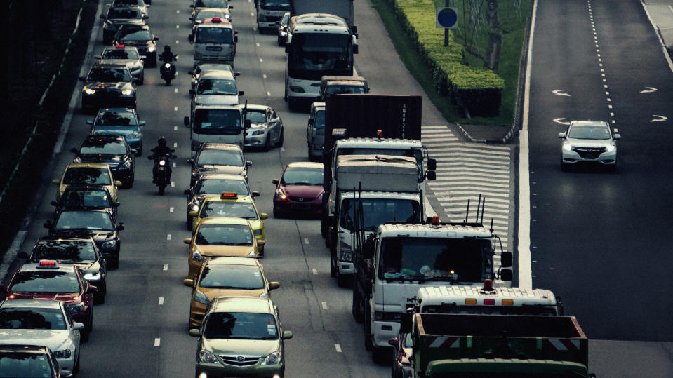 Cars, motorcycles, trucks, buses and lorries moving through dense traffic on a highway