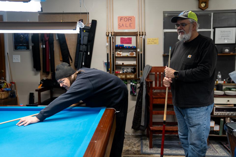 Doug Royer (left) and Ken Cunningham play billiards on Friday in downtown Perry as they discuss the shooting at Perry High School.