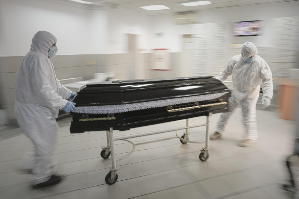FILE - Funeral house employees drag a coffin on a trolley as they arrive at the University Emergency Hospital morgue to take a COVID-19 victim for burial, in Bucharest, Romania, Monday, Nov. 8, 2021. In much of Eastern Europe, coronavirus deaths are high and vaccination rates are low, but politicians have hesitated to impose the measures curb the virus that experts are calling for. A World Health Organization official declared earlier this month that Europe is again the epicenter of the coronavirus pandemic. (AP Photo/Vadim Ghirda, File)
