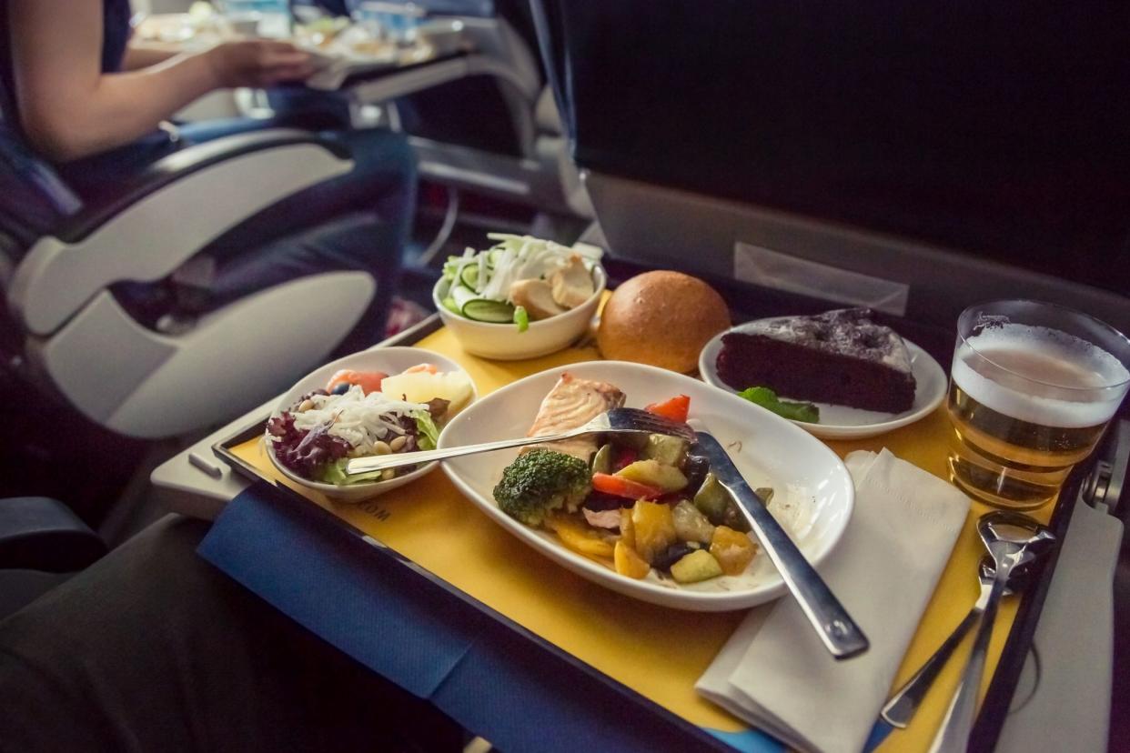 Passenger eats food on Board the plane. Food served on board of business class airplane on the table. Tray of food in the airplane. Tray of food on the plane, business class travel.