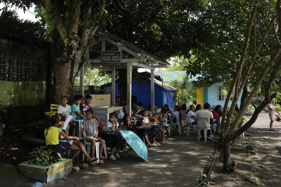 Students hold class under trees as the school was converted into a temporary evacuation center at Malilipot town, Albay province, northeastern Philippines, Thursday, June 15, 2023. Thousands of residents have left the mostly poor farming communities within a 6-kilometer (3.7-mile) radius of Mayon's crater in forced evacuations since volcanic activity spiked last week. (AP Photo/Aaron Favila)