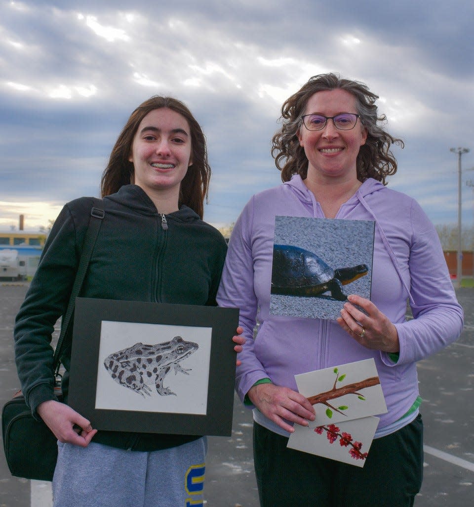 Sharon Pesci, left, and her daughter Mia Pesci talk about their art while they wait to board the Jet Express Ferry for the West Sister Island Sunset Cruise hosted by the Friends of Ottawa National Wildlife Refuge on Saturday. The Pescis will sell their art at the Wildlife Stop and Shop on May 13 and 14.