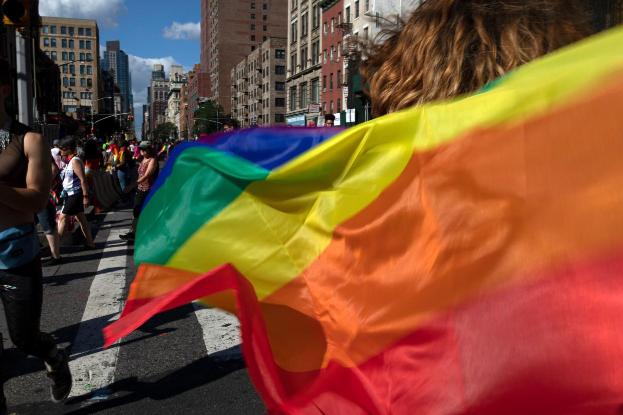 FILE - In this June 30, 2019, file photo parade-goers carrying rainbow flags walk down a street during the LBGTQ Pride march in New York, to celebrate five decades of LGBTQ pride, marking the 50th anniversary of the police raid that sparked the modern-day gay rights movement. 