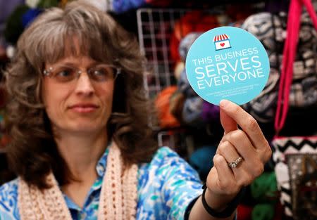 Elizabeth Ladd, owner of River Knits Fine Yarns, poses while holding up a "This businesses serves everyone" sticker she plans to place outside her business in downtown Lafayette, Indiana March 31, 2015. REUTERS/Nate Chute