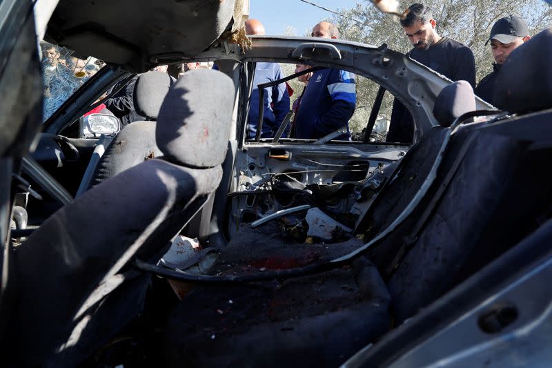 People check a damaged car where three Palestinian militants were killed during an Israeli operation, near Jenin