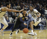 Marquette's Markus Howard (0) dribbles past Butler's Bryce Nze (10) and Henry Baddley (20) during the second half of an NCAA college basketball game, Friday, Jan. 24, 2020, in Indianapolis. Butler won, 89-85, in overtime. (AP Photo/Darron Cummings)