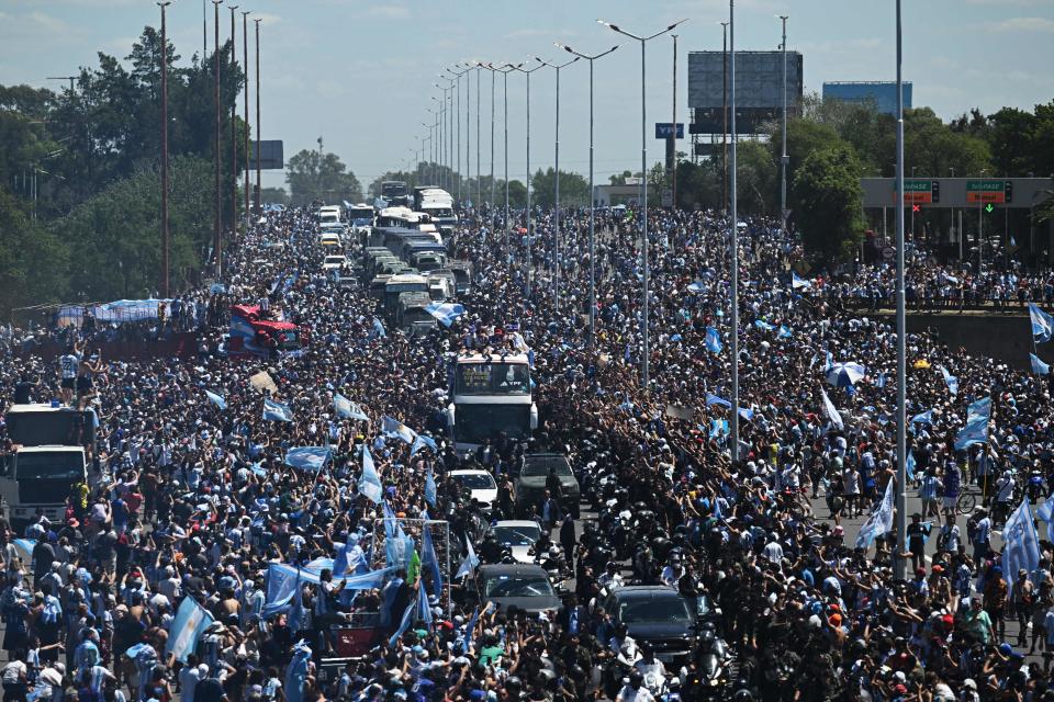 Argentina's players celebrate on board a bus with supporters after winning the Qatar 2022 World Cup tournament as they tour through Buenos Aires' downtown on December 20, 2022. - Millions of ecstatic fans are expected to cheer on their heroes as Argentina's World Cup winners led by captain Lionel Messi began their open-top bus parade of the capital Buenos Aires on Tuesday following their sensational victory over France. (Photo by Luis ROBAYO / AFP) (Photo by LUIS ROBAYO/AFP via Getty Images)