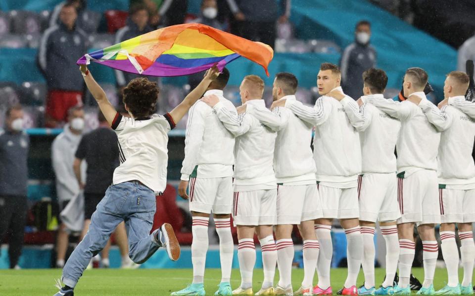 A person waving the rainbow flag runs on the pitch as the players line up for the national anthems the UEFA EURO 2020 Group F football match between Germany and Hungary at the Allianz Arena in Munich - GETTY IMAGES