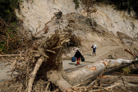 Villagers carry supplies over a road partially blocked by a landslide near the epicentre of a devastating earthquake at Lende Tovea village in Donggala, Sulawesi island, Indonesia October 6, 2018. REUTERS/Beawiharta