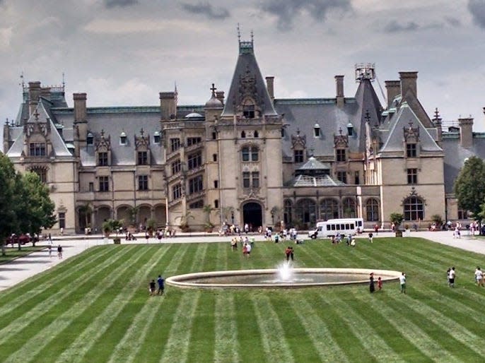 View of the Biltmore House, which is huge with a green lawn and trees