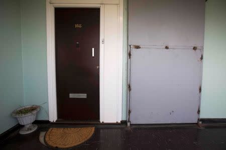 A resident front door is seen next to a boarded up apartment in a partially abandoned building on the Aylesbury Estate in south London, Britain October 15, 2015. REUTERS/Neil Hall