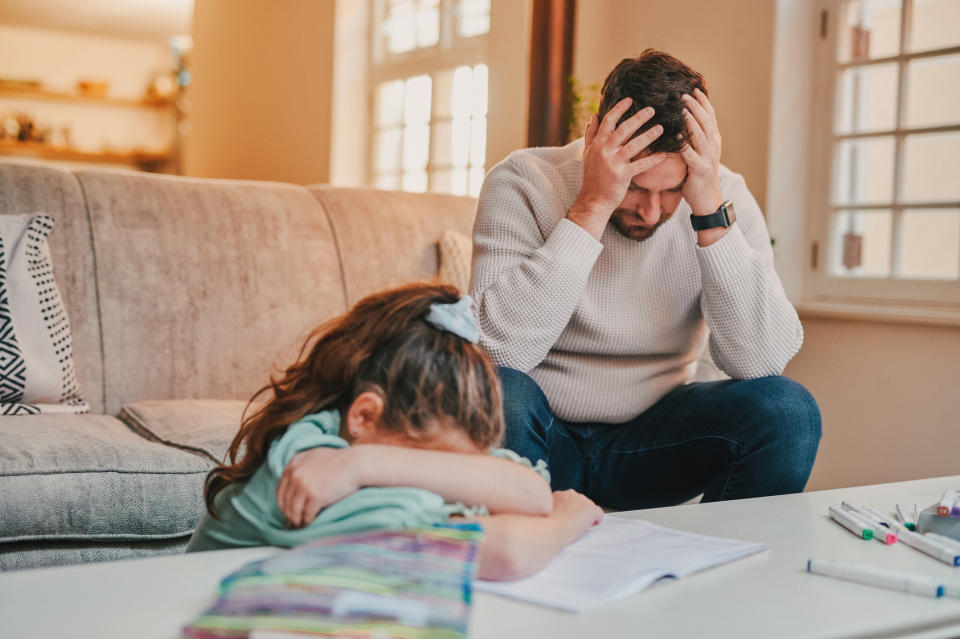 A dad and his daughter are sitting in a living room, frustrated with each other