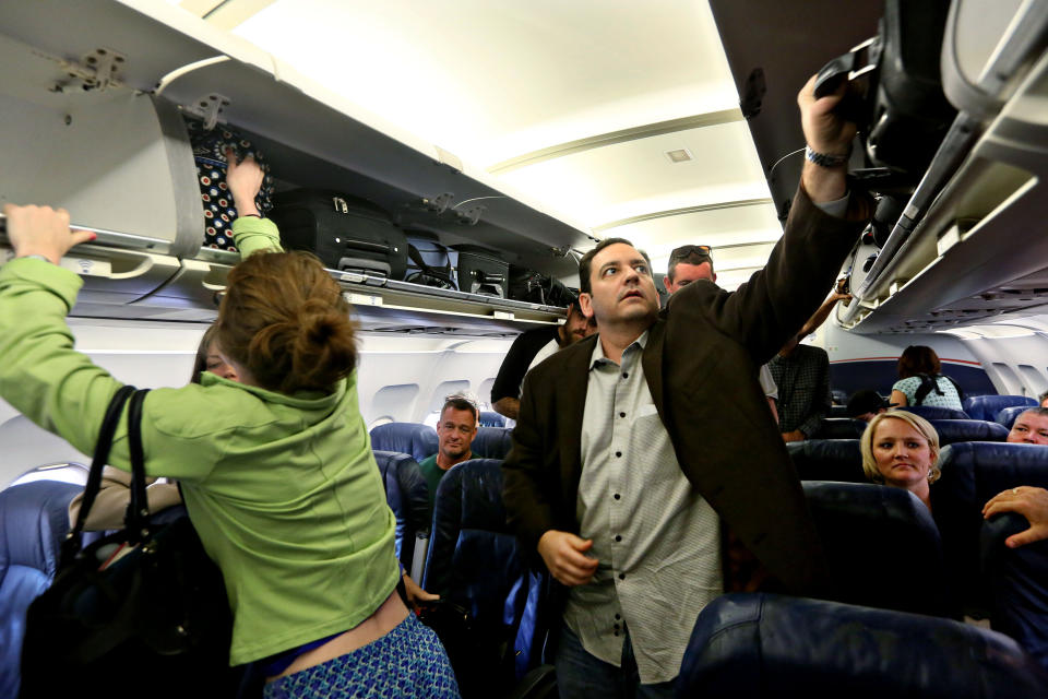 Passengers aboard a US Airways flight take their baggage from the overhead bin as they depart the plane in Phoenix, AZ on Oct. 7, 2013.&nbsp;