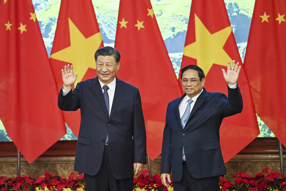 Vietnam's Prime Minister Pham Minh Chinh, right, and the China's President Xi Jinping wave to media members as they pose for a photo during a meeting at the government office in Hanoi, Vietnam, Wednesday, Dec. 13, 2023. (Nhac Nguyen/Pool Photo via AP)