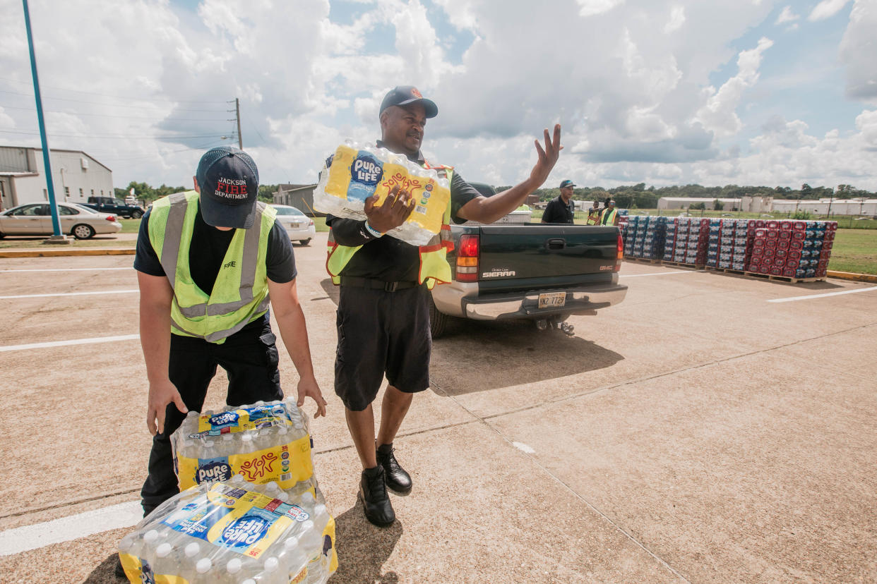 Members of the fire department distribute water at Hawkins Field Airport in Jackson, Miss., on Aug. 30, 2022. (Imani Khayyam for NBC News)