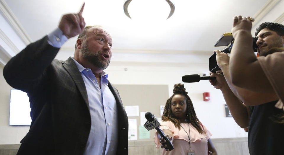 Alex Jones talks to media during a midday break during the trial at the Travis County Courthouse in Austin, Texas, Tuesday, July 26, 2022. An attorney for the parents of one of the children who were killed in the Sandy Hook Elementary School shooting told jurors that Jones repeatedly “lied and attacked the parents of murdered children” when he told his Infowars audience that the 2012 attack was a hoax. Attorney Mark Bankston said during his opening statement to determine damages against Jones that Jones created a “massive campaign of lies” and recruited “wild extremists from the fringes of the internet ... who were as cruel as Mr. Jones wanted them to be" to the victims' families. Jones later blasted the case, calling it a “show trial” and an assault on the First Amendment. (Briana Sanchez/Austin American-Statesman via AP, Pool)