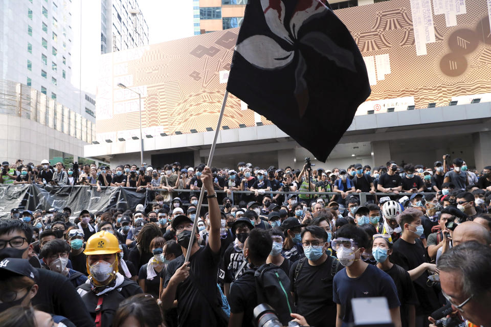 A protestor waves a black version of the Hong Kong flag outside the police headquarters in Hong Kong, Friday, June 21, 2019. More than 1,000 protesters blocked Hong Kong police headquarters into the evening Friday, while others took over major streets as the tumult over the city's future showed no signs of abating. (AP Photo/Kin Cheung)