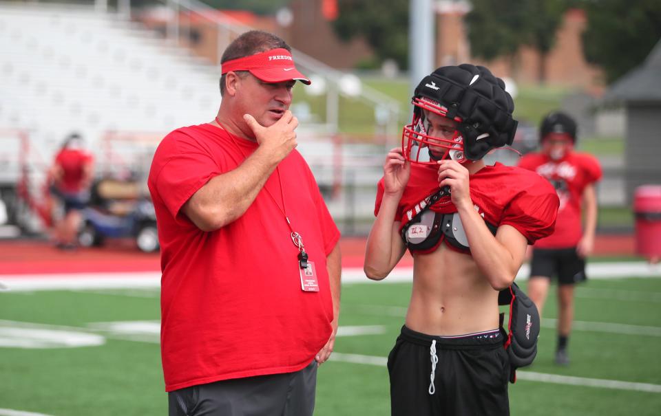 Freedom head coach John Rosa talks to quarterback Isaiah Leasha during the first part of training camp at Freedom High School on August 9, 2022. 