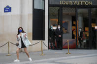 A woman gestures in front of a luxury shop that opens Monday, May 11, 2020 in Paris. he French began leaving their homes and apartments for the first time in two months without permission slips as the country cautiously lifted its lockdown. Clothing stores, coiffures and other businesses large and small were reopening on Monday _ with strict precautions to keep the coronavirus at bay. (AP Photo/Francois Mori)