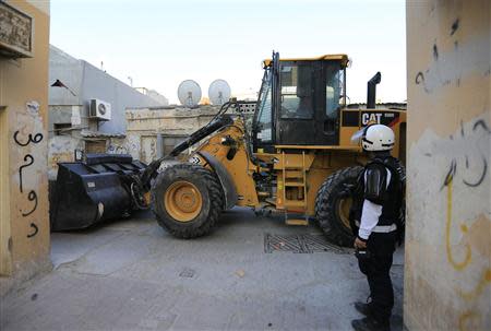 A wheel dozer is seen removing road-blocks set up by anti-government protesters in the village of Karanna, west of Manama, February 13, 2014. REUTERS/Hamad I Mohammed