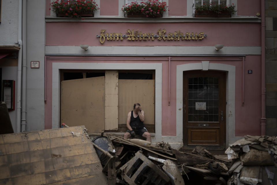 A man takes a break from cleaning up debris from the flood disaster in Bad Neuenahr-Ahrweiler, Germany, Monday July 19, 2021. More than 180 people died when heavy rainfall turned tiny streams into raging torrents across parts of western Germany and Belgium, and officials put the death toll in Ahrweiler county alone at 110. (AP Photo/Bram Janssen)