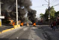 <p>People walk past a barricade during a protest over the cost of fuel in Port-au-Prince, Haiti, Saturday, July 7, 2018. (Photo: Dieu Nalio Chery/AP) </p>