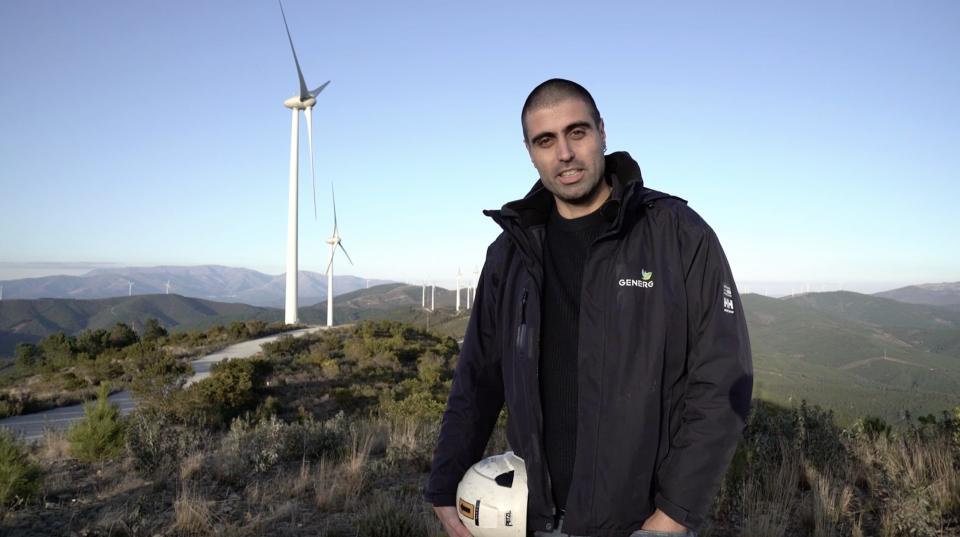 Portuguese wind turbine technician João Sardo carries his helmet in his hand as he is interviewed at a worksite.