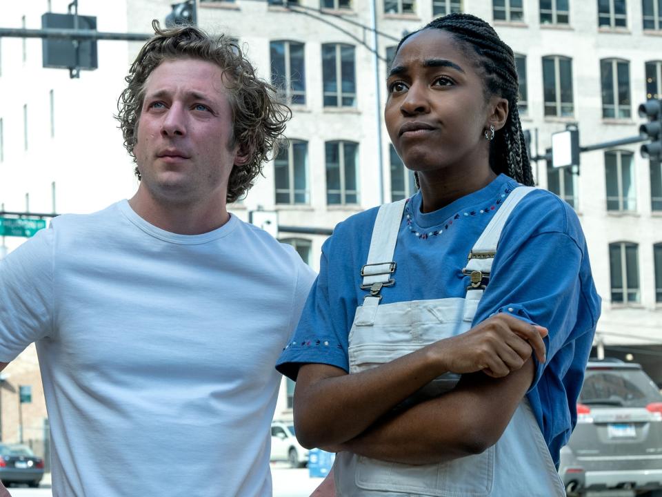 jeremy allen white and ayo edebiri in the bear, standing with puzzled expressions on their faces on a street