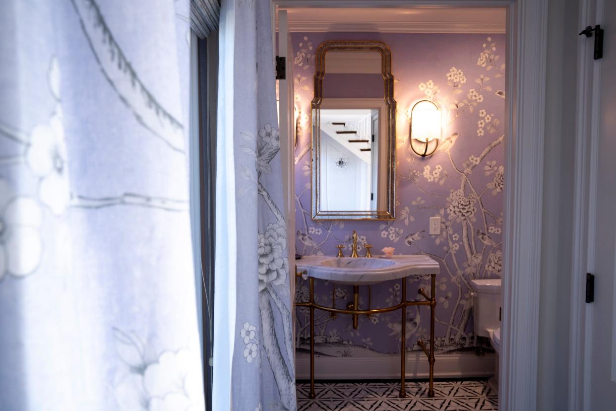 A powder room decorated with wallpaper panels that create a room-sized mural with a floral design.